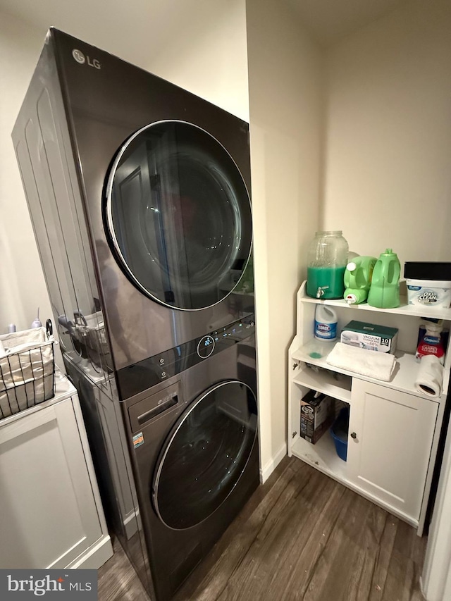 washroom with dark wood finished floors and stacked washer / dryer