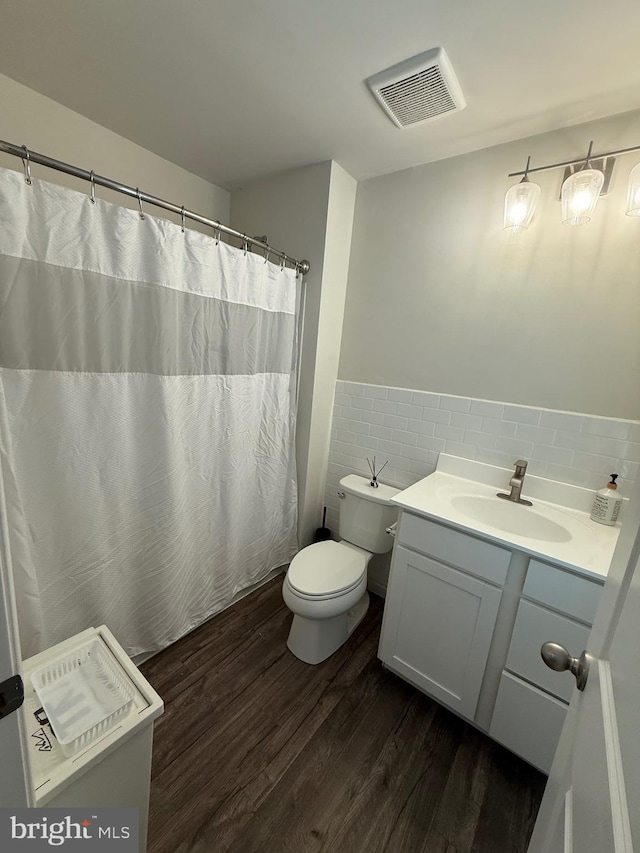 full bath with visible vents, tile walls, wood finished floors, vanity, and toilet