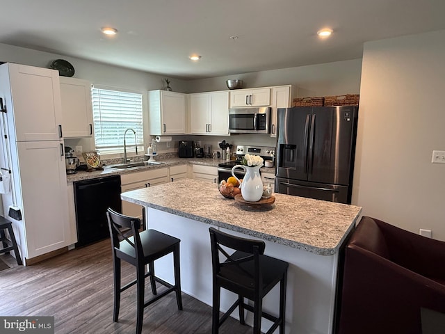 kitchen featuring a sink, light countertops, white cabinets, black appliances, and a breakfast bar