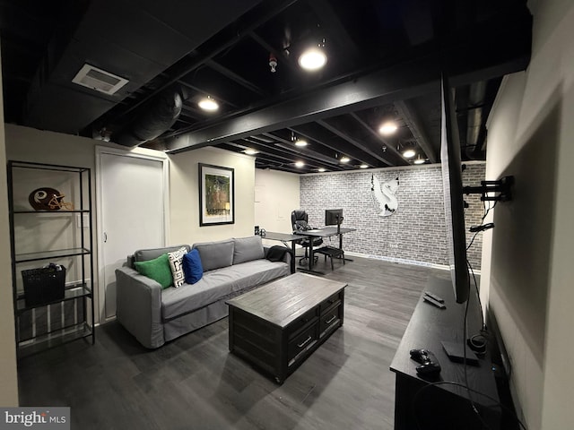 living area with brick wall, wood finished floors, and visible vents