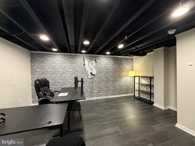 unfurnished office with baseboards, wood finished floors, and brick wall