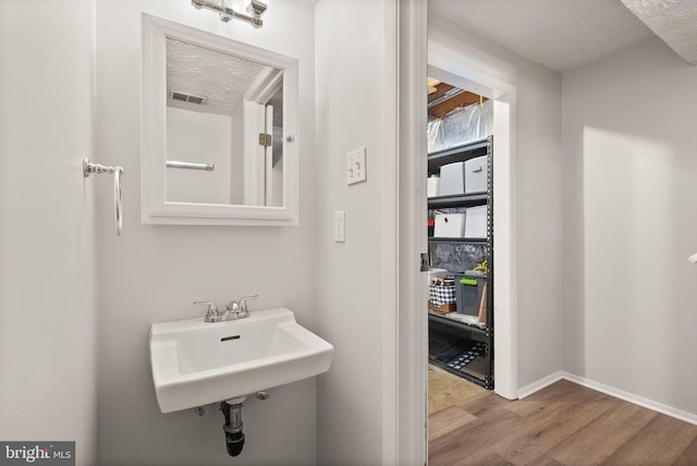 8337 Wind Fall Rd, Springfield, VA 22153 - bathroom featuring wood finished floors, a textured ceiling, a sink, and baseboards