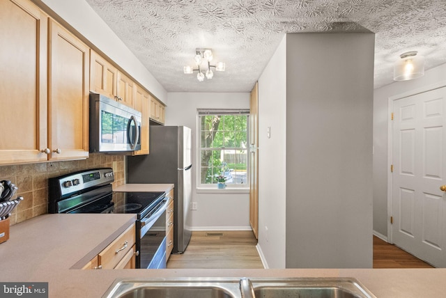 8337 Wind Fall Rd, Springfield, VA 22153 - kitchen with appliances with stainless steel finishes, light wood-type flooring, backsplash, light brown cabinetry, and a textured ceiling