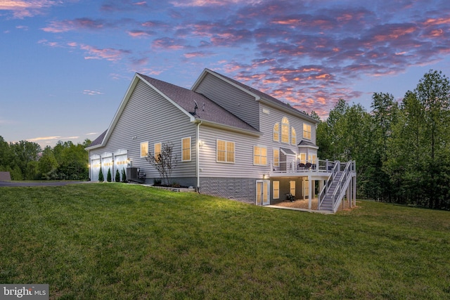 back of house featuring a lawn, stairway, a deck, a garage, and central AC