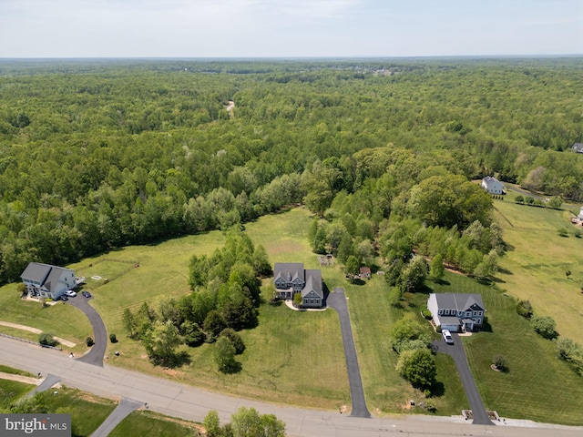 aerial view of property and surrounding area featuring a heavily wooded area