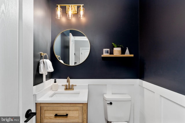 half bath with toilet, vanity, and wainscoting