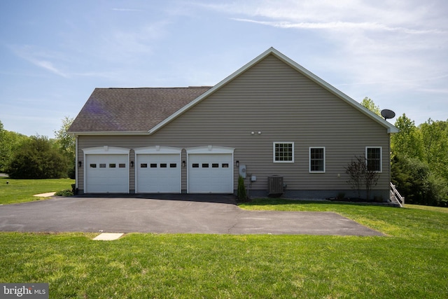 view of side of home with central AC, driveway, a garage, and a lawn