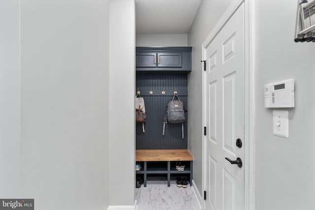 mudroom with marble look tile flooring and baseboards