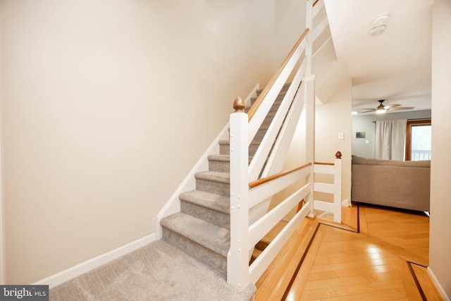 staircase featuring baseboards, ceiling fan, and hardwood / wood-style flooring
