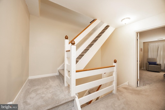 staircase featuring baseboards and carpet