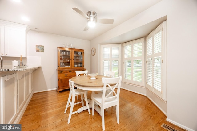 dining area featuring light wood-style floors, baseboards, and ceiling fan