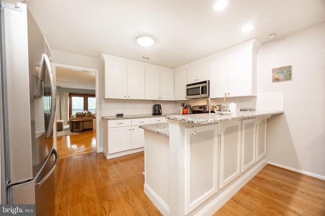 kitchen featuring baseboards, white cabinetry, a peninsula, light wood-style floors, and appliances with stainless steel finishes