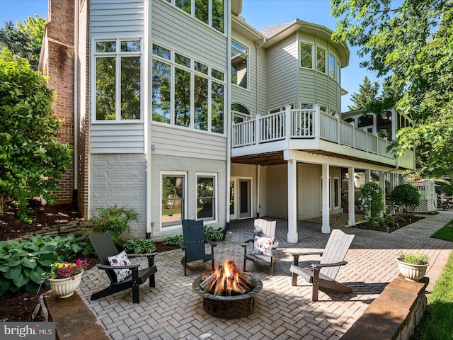 rear view of house featuring an outdoor fire pit, a patio, and brick siding