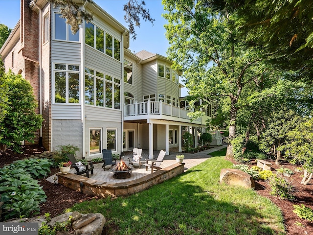 back of house with an outdoor fire pit, a patio area, a lawn, brick siding, and a wooden deck