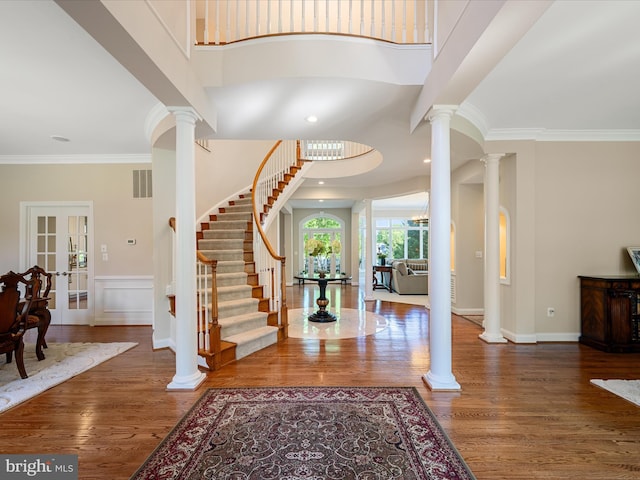 entryway featuring decorative columns, wood finished floors, stairway, ornamental molding, and french doors