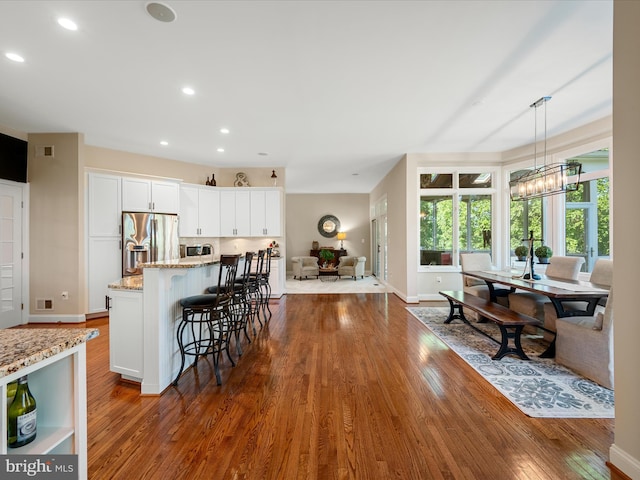 kitchen with stainless steel appliances, dark wood-style flooring, light stone countertops, baseboards, and white cabinets