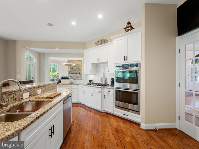 kitchen featuring a sink, stainless steel appliances, wood finished floors, white cabinets, and recessed lighting
