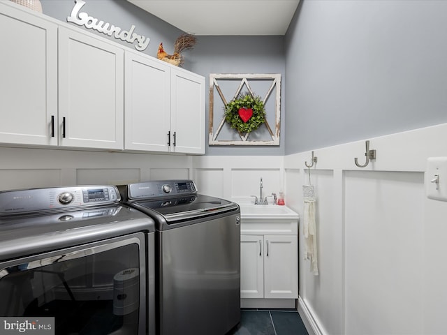 washroom featuring separate washer and dryer, cabinet space, dark tile patterned flooring, wainscoting, and a decorative wall