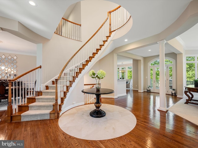 entryway with decorative columns, hardwood / wood-style flooring, healthy amount of natural light, stairs, and crown molding