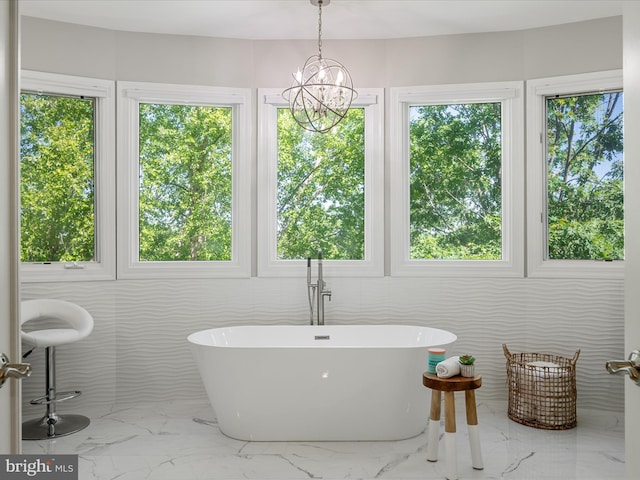 bathroom with marble finish flooring, a freestanding bath, plenty of natural light, and a chandelier