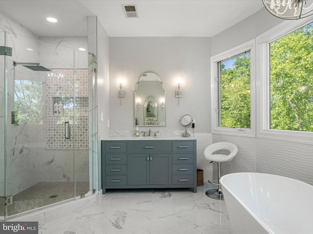 bathroom with marble tiled flooring, a freestanding tub, vanity, a marble finish shower, and wainscoting