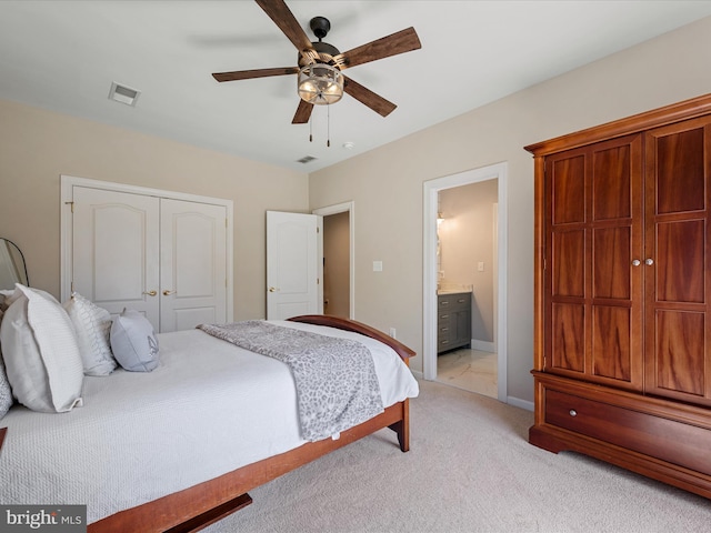 bedroom with a closet, light carpet, baseboards, ceiling fan, and ensuite bathroom