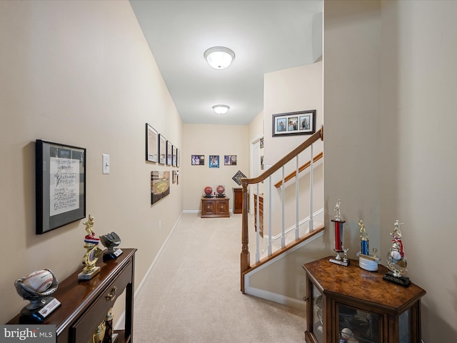 hallway featuring stairs, carpet flooring, and baseboards