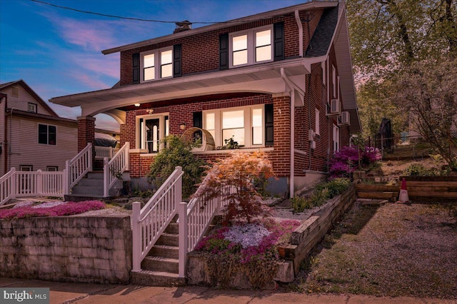 traditional style home with a porch, stairs, and brick siding