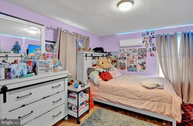 bedroom with multiple windows, light wood-type flooring, and an AC wall unit