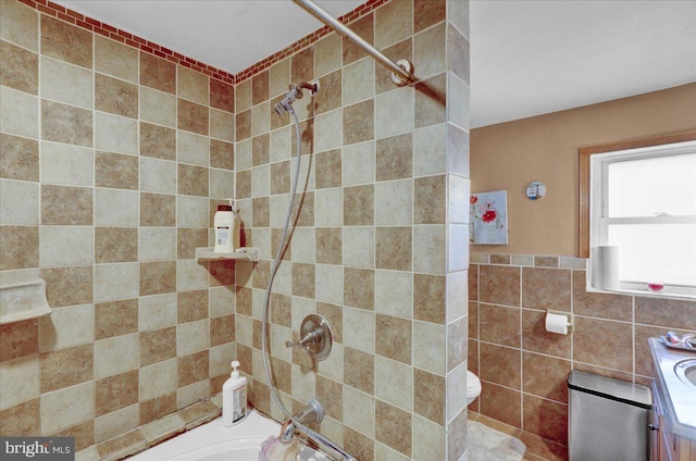 full bathroom with tile walls, vanity, and washtub / shower combination