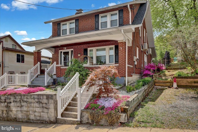 american foursquare style home featuring cooling unit, a porch, brick siding, and stairway