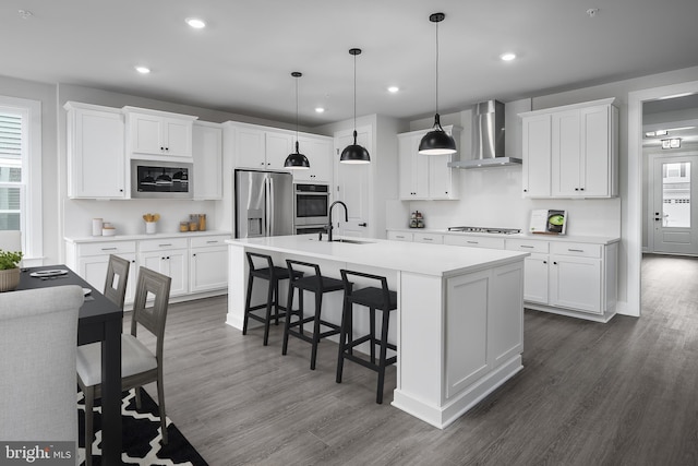 1219 Bear Branch Rd, Laurel, MD 20708 - kitchen with dark wood-style flooring, a breakfast bar area, wall chimney exhaust hood, a sink, and stainless steel appliances