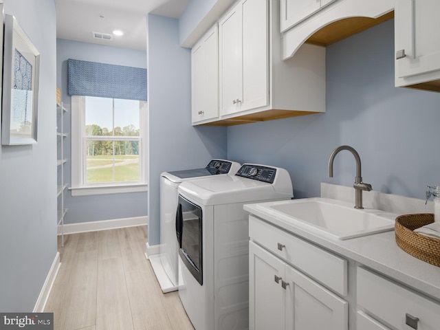 laundry room featuring visible vents, cabinet space, a sink, light wood-style floors, and washer and dryer