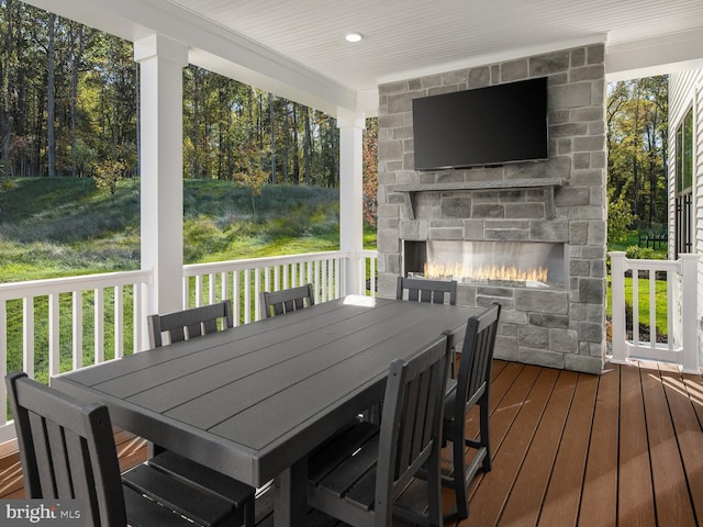 wooden terrace with outdoor dining space and an outdoor stone fireplace