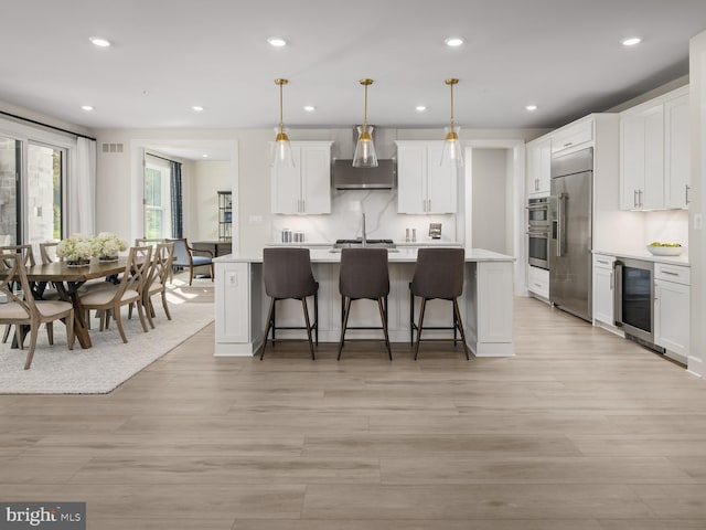 kitchen featuring white cabinets, appliances with stainless steel finishes, light countertops, recessed lighting, and wine cooler