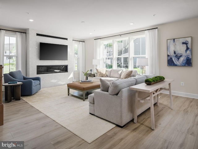 living area with recessed lighting, baseboards, a fireplace, and light wood-type flooring