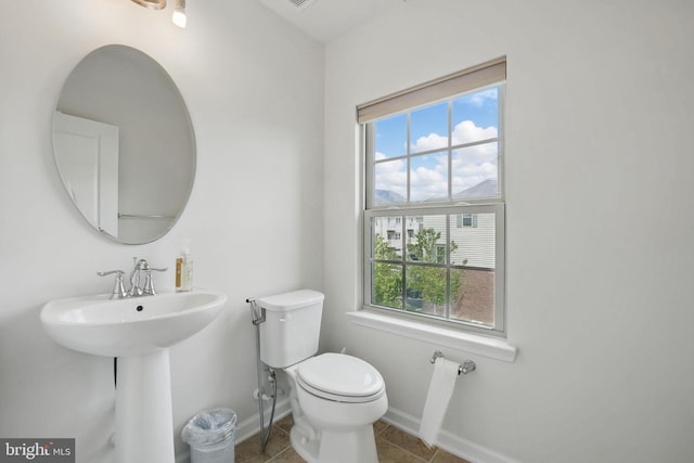 bathroom featuring a healthy amount of sunlight, baseboards, tile patterned flooring, and toilet
