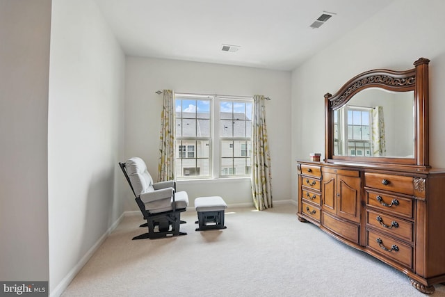 living area featuring baseboards, visible vents, and light carpet