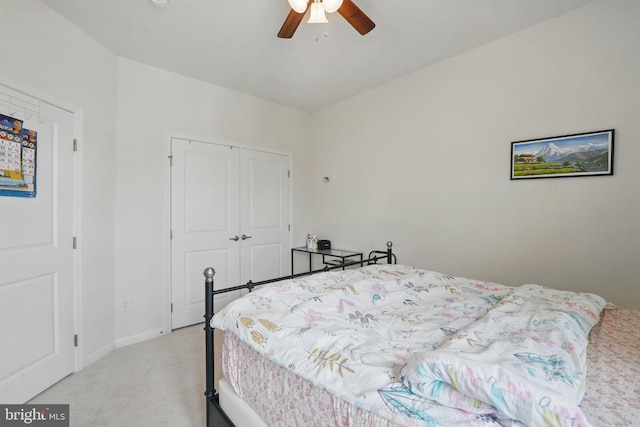 bedroom featuring ceiling fan, light carpet, baseboards, and a closet