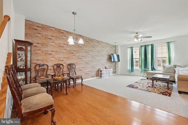 living area with baseboards, ceiling fan, vaulted ceiling, and wood finished floors