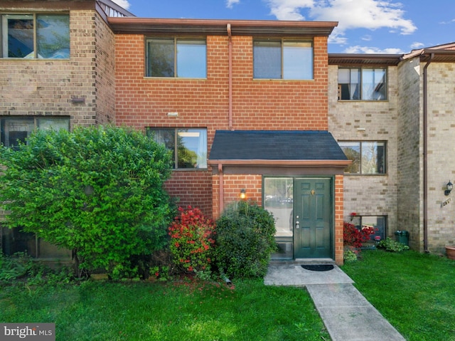 view of property featuring brick siding and a front lawn
