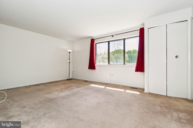 unfurnished bedroom featuring baseboards, carpet flooring, and visible vents