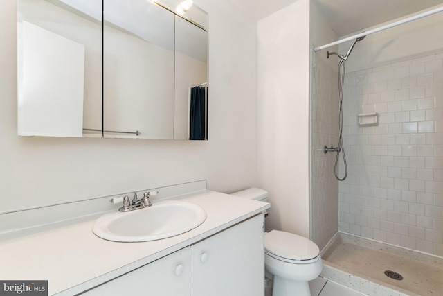 bathroom with vanity, toilet, and tiled shower