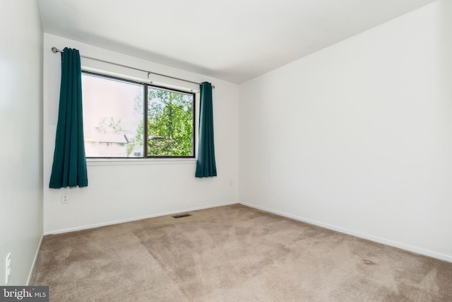 spare room with baseboards, carpet flooring, and visible vents