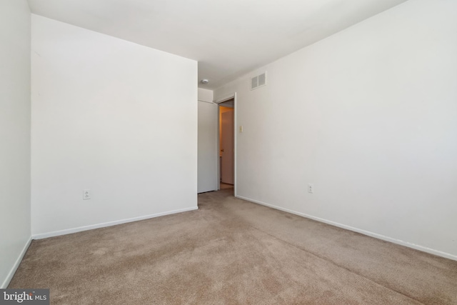 unfurnished room with baseboards, light colored carpet, and visible vents
