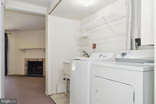 washroom featuring washing machine and clothes dryer, laundry area, light carpet, and a brick fireplace