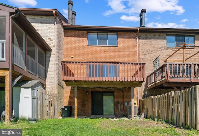back of property with central air condition unit, brick siding, a yard, and fence