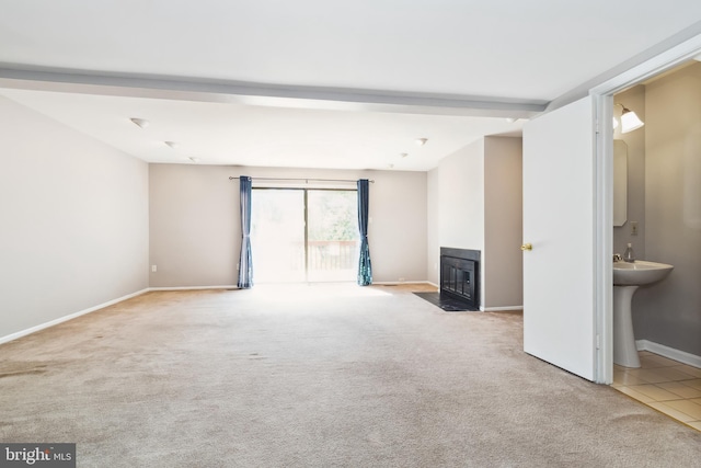 unfurnished living room featuring a fireplace with flush hearth, carpet floors, baseboards, and tile patterned floors