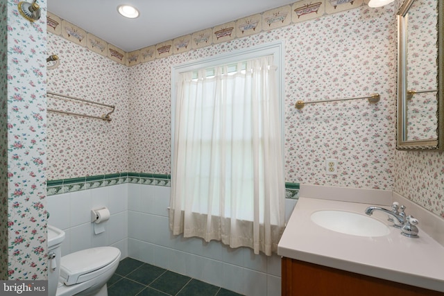 bathroom featuring vanity, tile patterned floors, a wainscoted wall, toilet, and wallpapered walls
