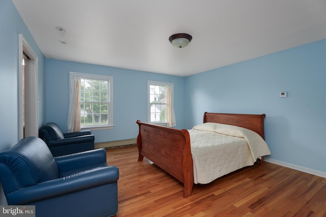 bedroom with baseboards, baseboard heating, and light wood-style flooring